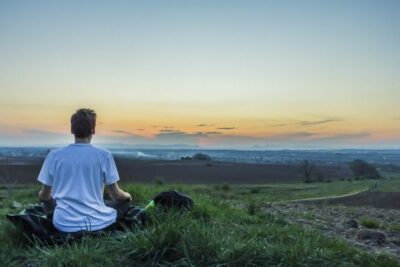 Man sitting outdoors looking at the city skyline under a clear sky