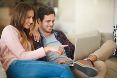 Young couple sitting together using a laptop to search for homes online