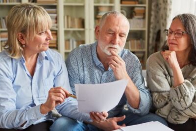 Older couple reviewing home selling paperwork with a real estate advisor in a living room