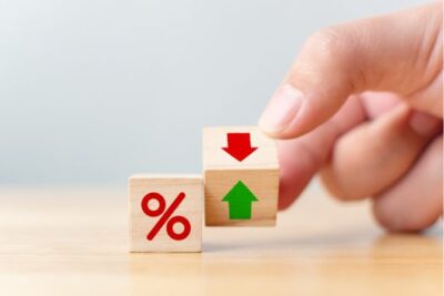 Hand holding wooden blocks with percentage sign and up or down arrows, symbolizing adjustable mortgage interest rates.