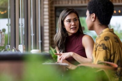Two women talking at a café about buying a home in DC, Maryland, or Virginia with guidance from Matt Cheney and Cheney and Co.