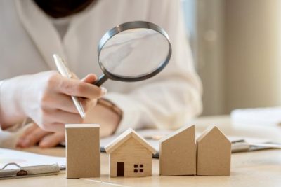 Home market analysis with magnifying glass and miniature wooden houses on desk