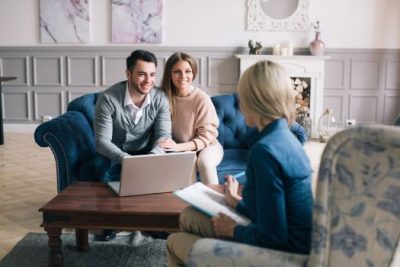 Smiling couple meeting with a real estate agent to discuss selling and buying a home at the same time