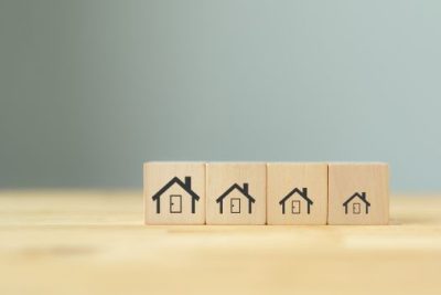 Wooden blocks with house icons in different sizes symbolizing varying housing market conditions across regions