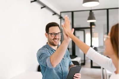 Young couple celebrating homebuying success with a high five after meeting with a real estate professional