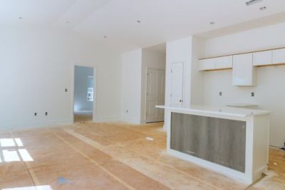 Interior of a newly built home under construction showing unfinished kitchen island and open living space with white walls